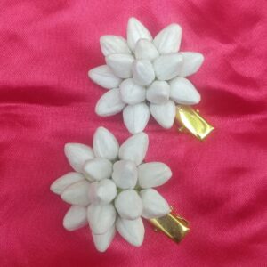 White floral hair clips with layered petal design and gold metal clasp on pink background