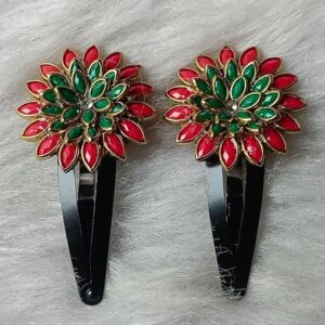 Red and green floral stone snap hair clips with gold detailing placed on a soft fur background.