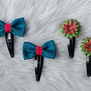 Teal cloth bow hair clips and red-green floral stone snap clips arranged on a soft fur background.