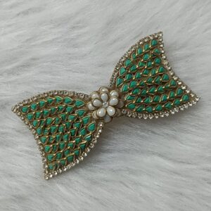 Gold-tone green Kundan bow hair clip with floral center accent on soft background