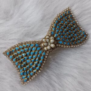 Gold-tone turquoise blue Kundan bow hair clip with floral center accent on soft background