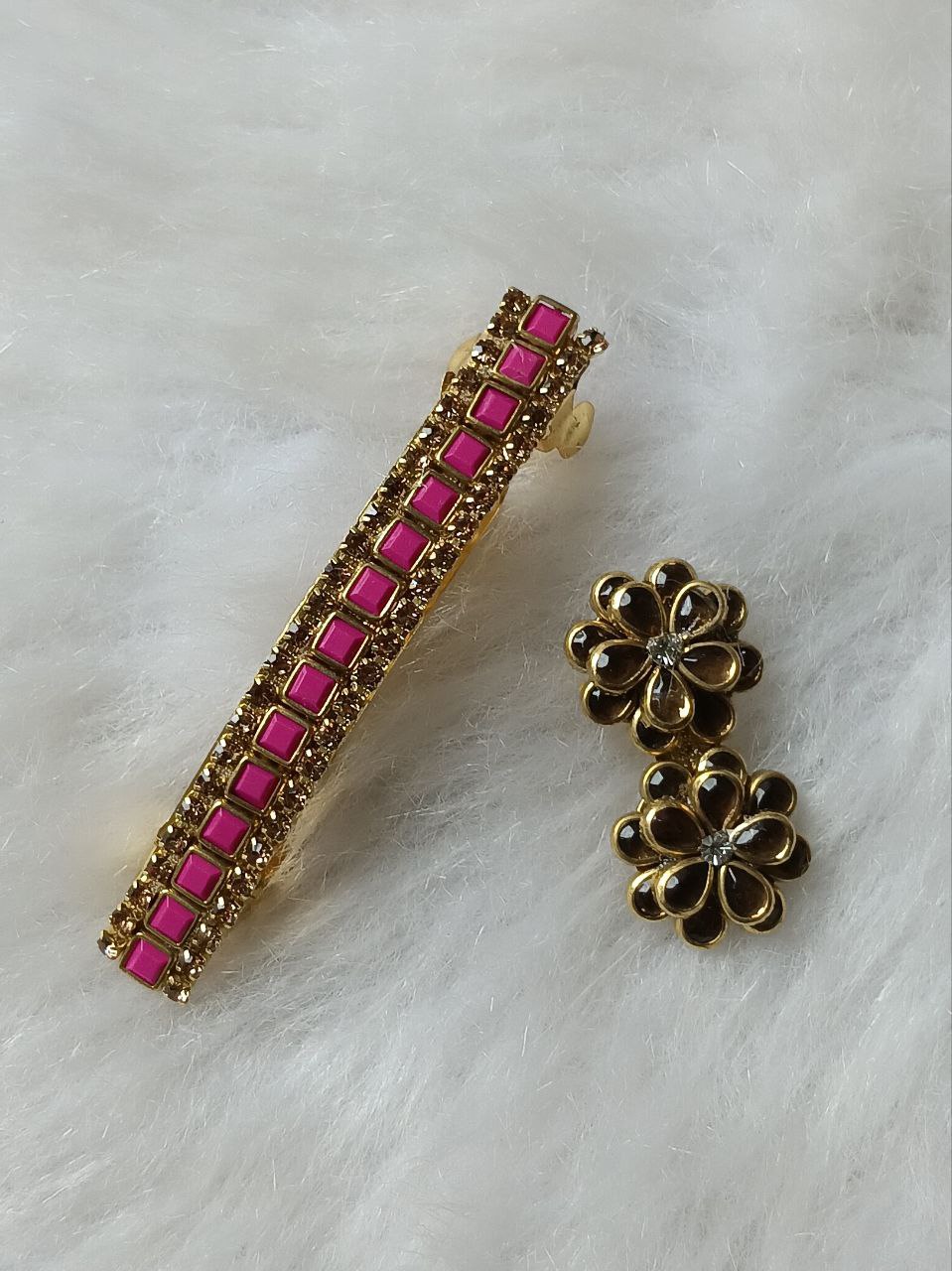 Pink Stone Floral Stud Earrings in Gold Tone Finish Gold-tone floral stud earrings featuring pink square-cut stones arranged in a flower design on a soft white background