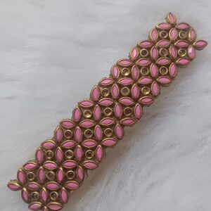 Handcrafted pink and gold Kundan stone hair clip on a white textured background.