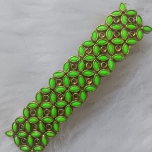 Close-up of a handcrafted rectangular gold-toned hair clip adorned with neon green Kundan stones.